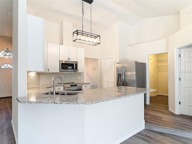 kitchen with high vaulted ceiling, light stone counters, a sink, appliances with stainless steel finishes, and a peninsula