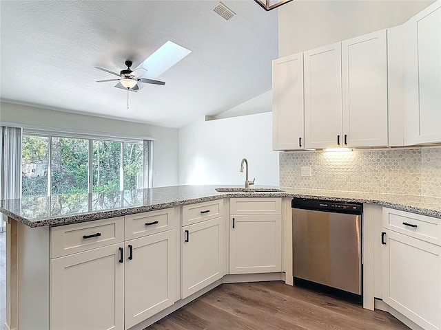 kitchen featuring visible vents, a sink, wood finished floors, a peninsula, and dishwasher