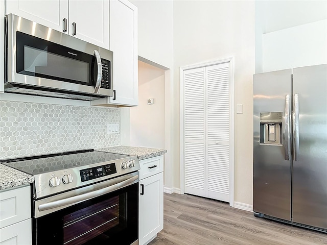 kitchen featuring light wood-style flooring, light stone countertops, backsplash, and stainless steel appliances