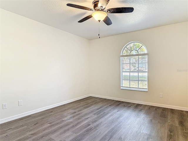 empty room featuring dark wood-style floors, ceiling fan, a textured ceiling, and baseboards