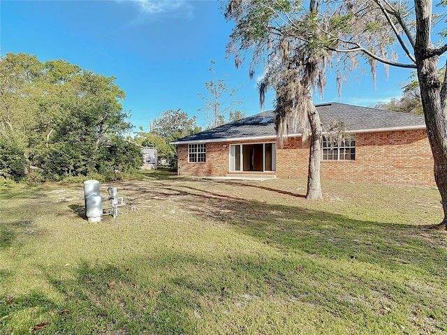 back of property with a lawn and brick siding