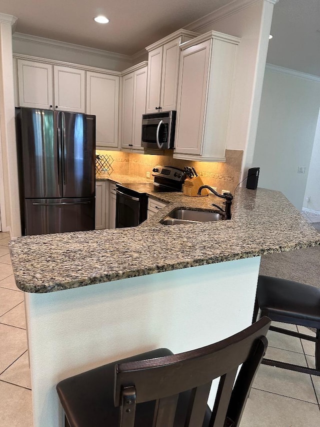 1812 Leather Fern Dr, Ocoee, FL 34761 - kitchen featuring stainless steel appliances, a sink, light tile patterned floors, dark stone countertops, and ornamental molding