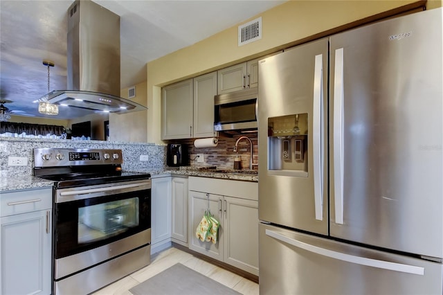 kitchen with light stone countertops, visible vents, island exhaust hood, stainless steel appliances, and backsplash