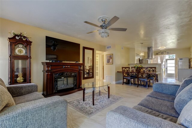 living room featuring a high end fireplace, visible vents, baseboards, and a ceiling fan