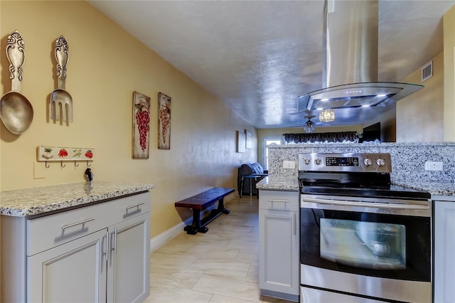 kitchen featuring visible vents, island exhaust hood, stainless steel electric range oven, and light stone countertops