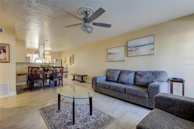 living area with visible vents, baseboards, and a ceiling fan