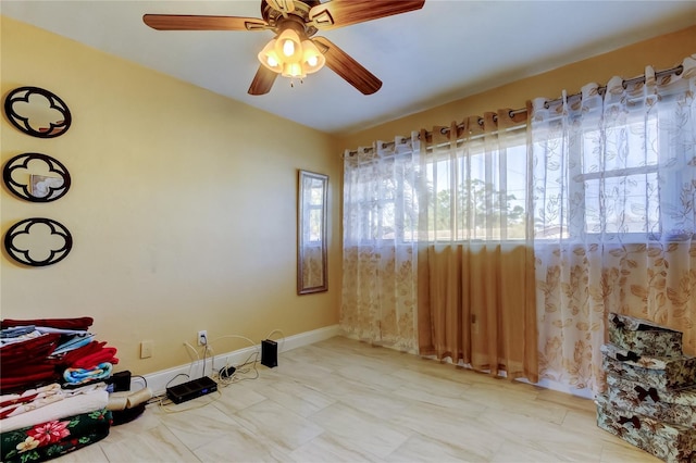 unfurnished room featuring ceiling fan and baseboards