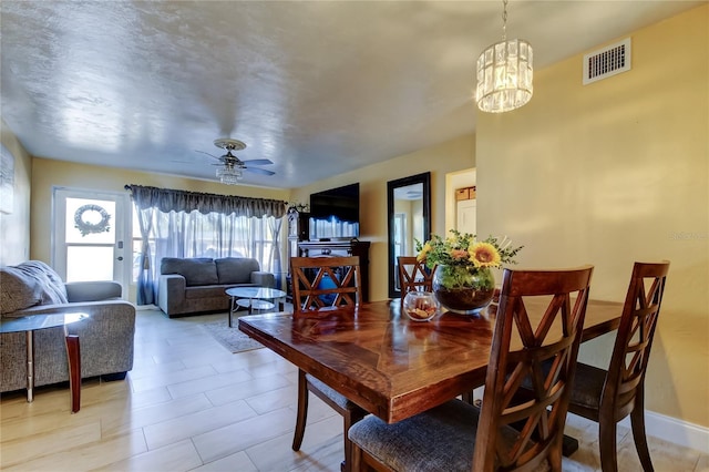 dining space featuring visible vents, ceiling fan with notable chandelier, and baseboards