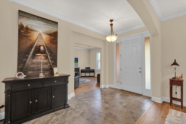 entrance foyer with baseboards, arched walkways, ornamental molding, and light wood finished floors