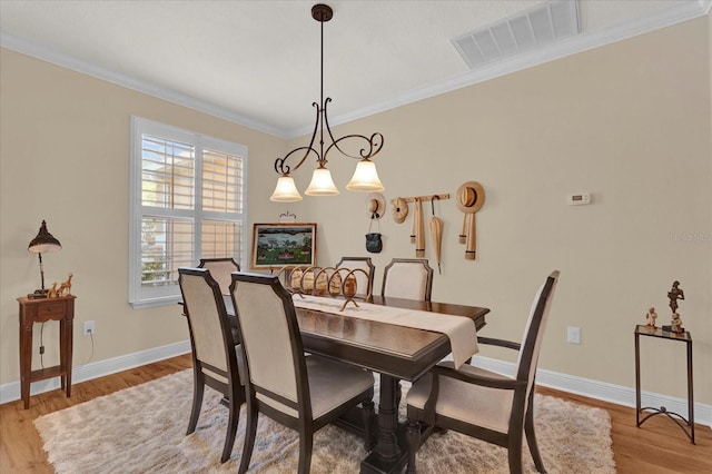 dining room with visible vents, baseboards, wood finished floors, and crown molding