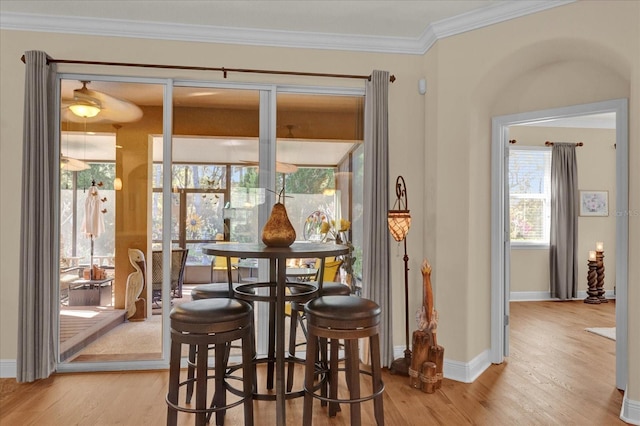 dining space featuring light wood-style floors, baseboards, and ornamental molding