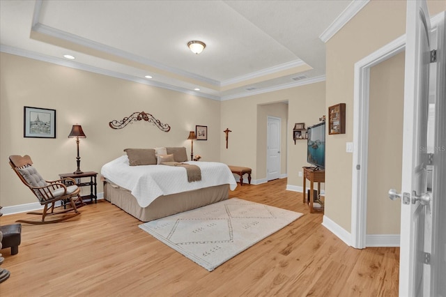 bedroom with baseboards, visible vents, crown molding, light wood-style floors, and a raised ceiling