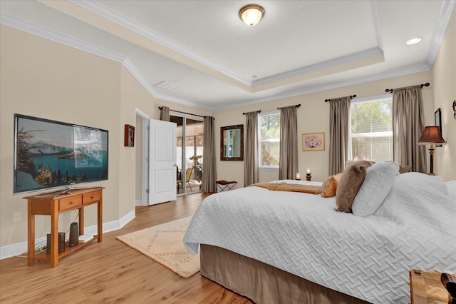 bedroom featuring crown molding, baseboards, light wood-type flooring, and a tray ceiling