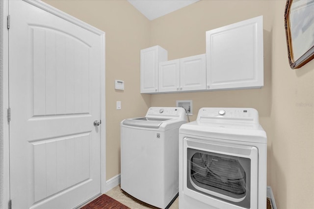 clothes washing area featuring baseboards, cabinet space, and separate washer and dryer