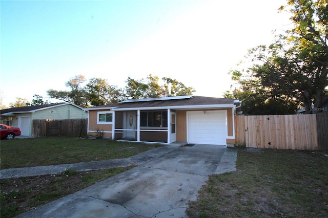 view of front of home featuring solar panels, fence, concrete driveway, a front yard, and a garage