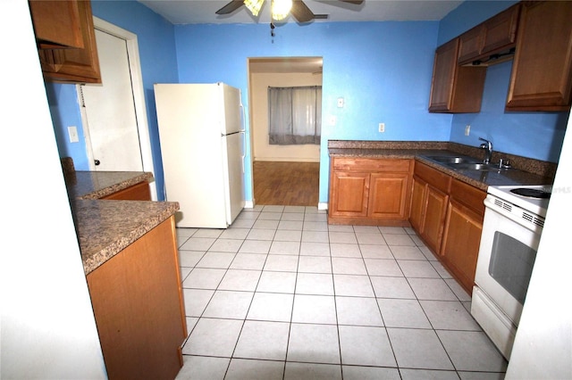 kitchen with a ceiling fan, a sink, dark countertops, white appliances, and light tile patterned floors