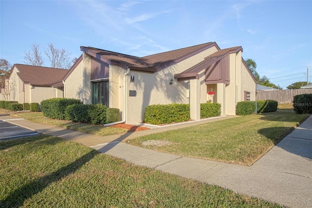 view of home's exterior with stucco siding, a yard, and fence