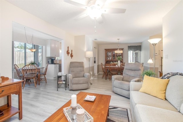 living room featuring a wealth of natural light, light wood-style floors, and ceiling fan