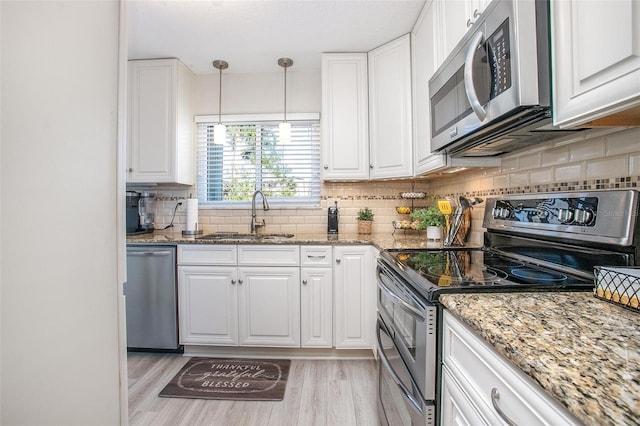 kitchen featuring white cabinets, appliances with stainless steel finishes, light wood-type flooring, and a sink