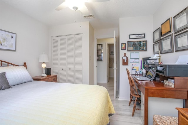 bedroom with visible vents, wood finished floors, a closet, baseboards, and ceiling fan