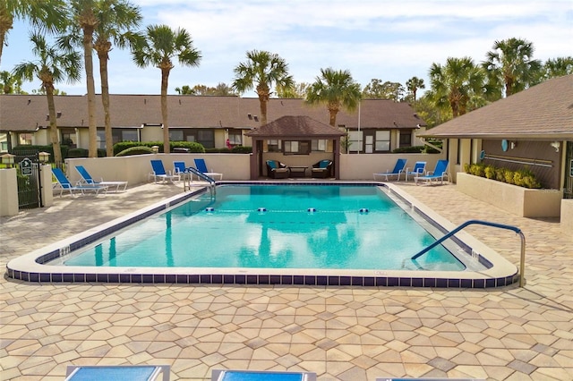 pool featuring a gazebo, a patio area, fence, and a residential view