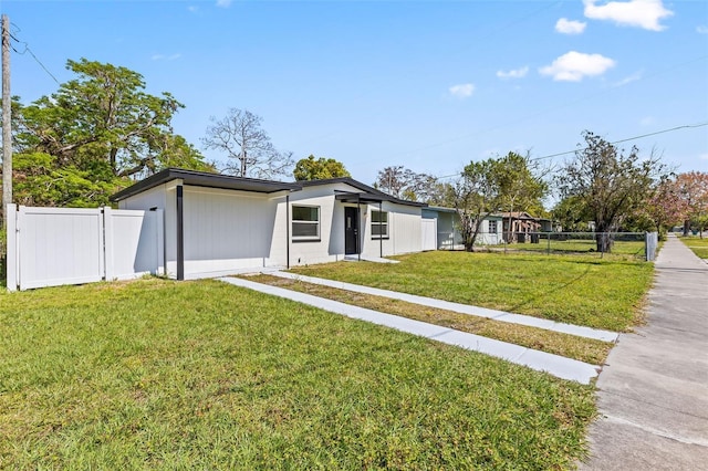 mid-century modern home featuring a front lawn and fence