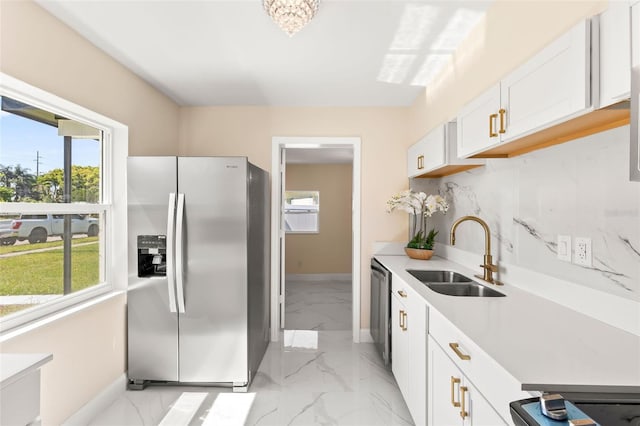 kitchen featuring a sink, light countertops, marble finish floor, appliances with stainless steel finishes, and tasteful backsplash