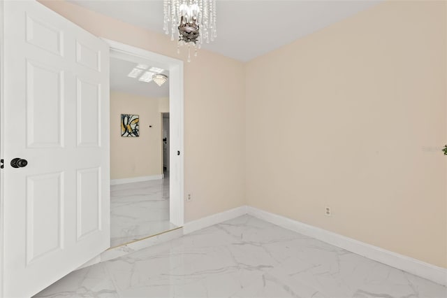 empty room featuring a notable chandelier, baseboards, and marble finish floor