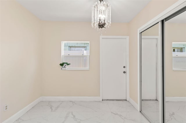 entrance foyer featuring marble finish floor, baseboards, and an inviting chandelier