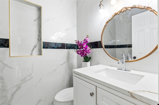 bathroom featuring toilet, vanity, and tile walls