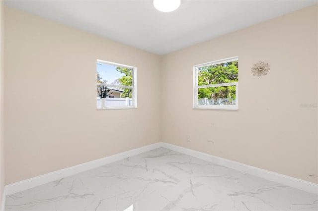 spare room with plenty of natural light, baseboards, and marble finish floor