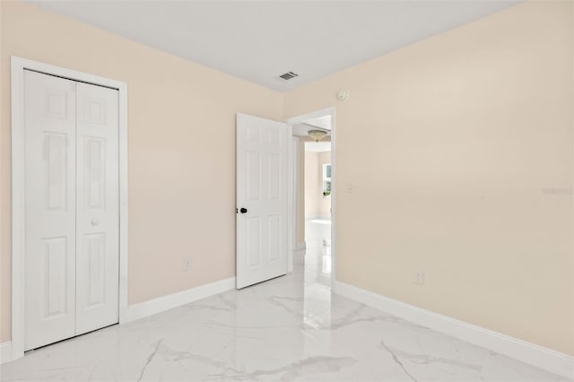 unfurnished bedroom with visible vents, baseboards, marble finish floor, and a closet