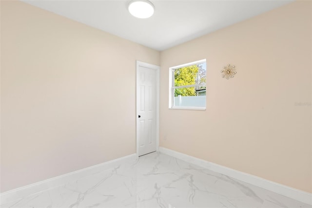 unfurnished room featuring marble finish floor and baseboards