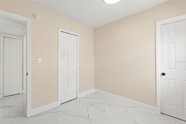 unfurnished bedroom featuring a closet, marble finish floor, and baseboards