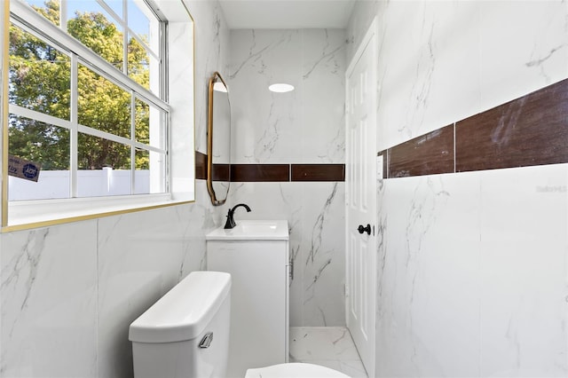 bathroom featuring marble finish floor, stone wall, and a sink