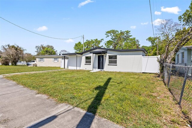 mid-century home featuring a front lawn and fence