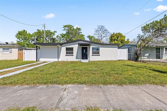 mid-century home with a front lawn and fence