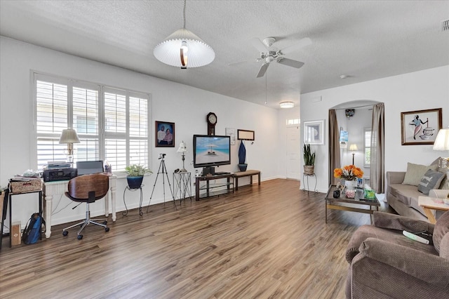 living room with arched walkways, a textured ceiling, a ceiling fan, and wood finished floors