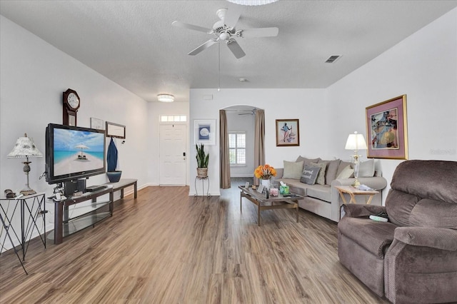 living area with arched walkways, visible vents, a ceiling fan, and wood finished floors