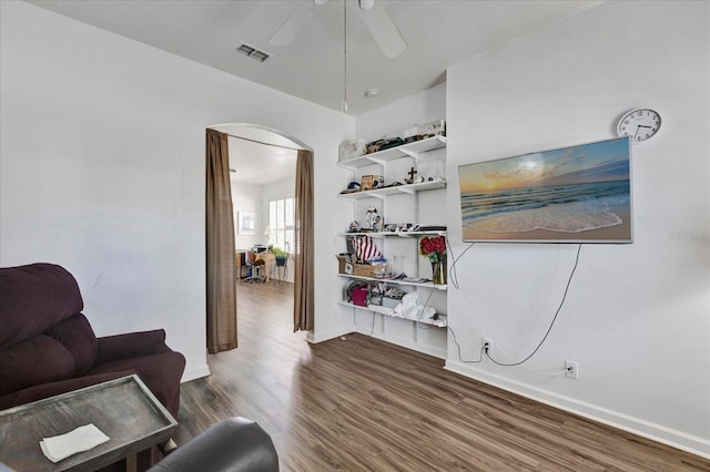 living area with visible vents, wood finished floors, arched walkways, baseboards, and ceiling fan