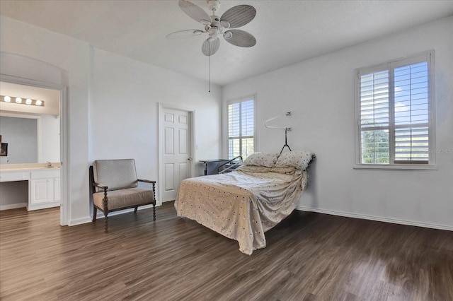 bedroom featuring baseboards, built in desk, ensuite bathroom, wood finished floors, and a ceiling fan