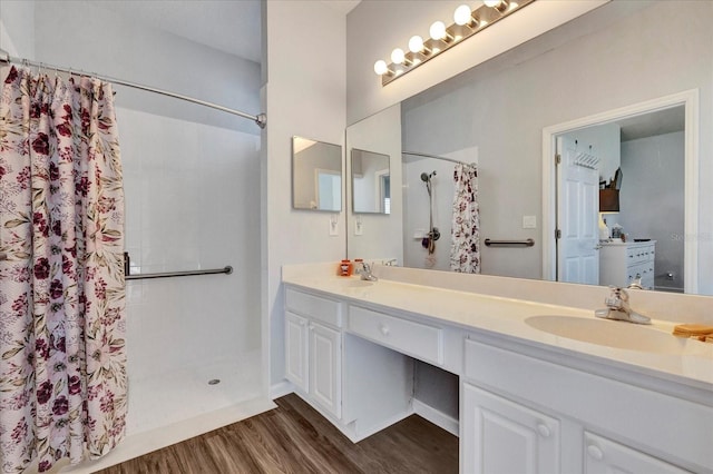 bathroom featuring double vanity, wood finished floors, a shower with shower curtain, and a sink