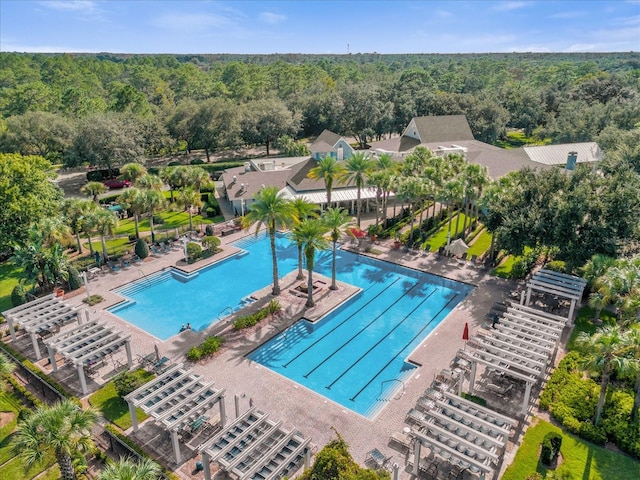 community pool featuring a patio, a pergola, a forest view, and fence