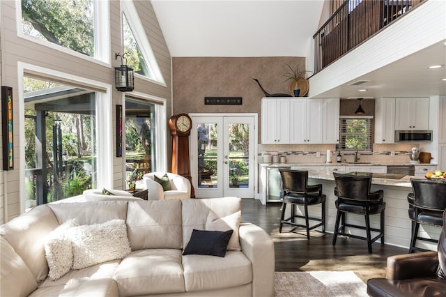 living area with dark wood finished floors, visible vents, french doors, and a towering ceiling