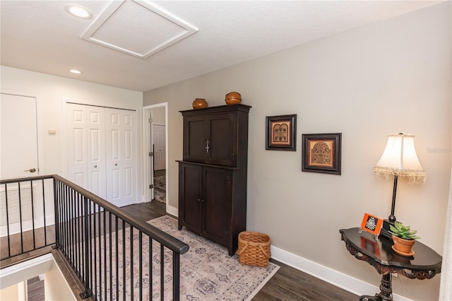 hallway featuring an upstairs landing, wood finished floors, recessed lighting, baseboards, and attic access