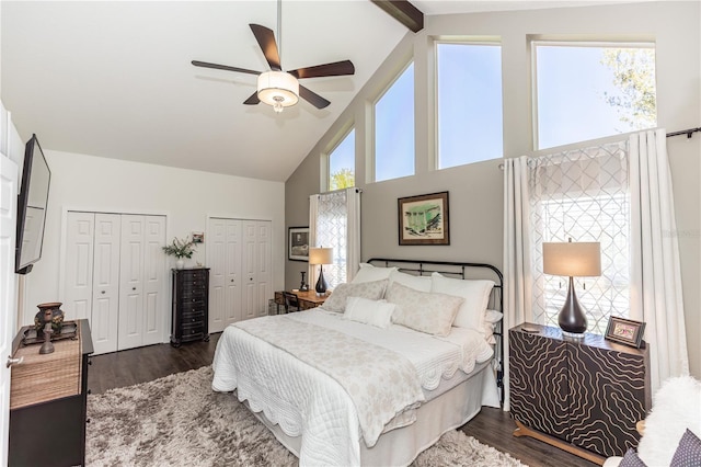 bedroom with beamed ceiling, multiple closets, high vaulted ceiling, a ceiling fan, and dark wood finished floors