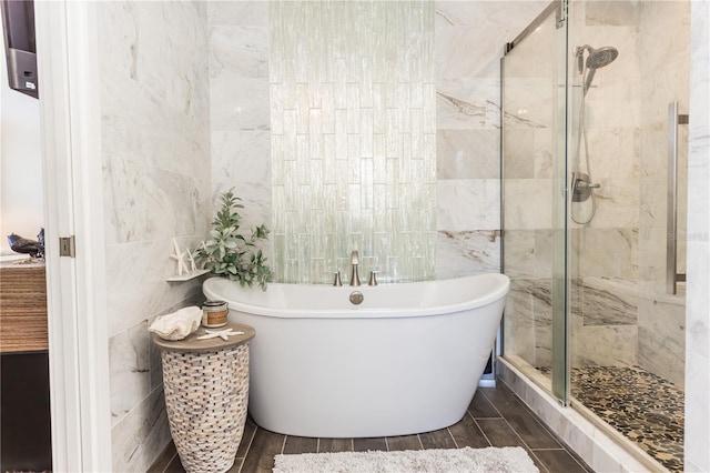 full bath with wood finish floors, a freestanding bath, tile walls, and a shower stall