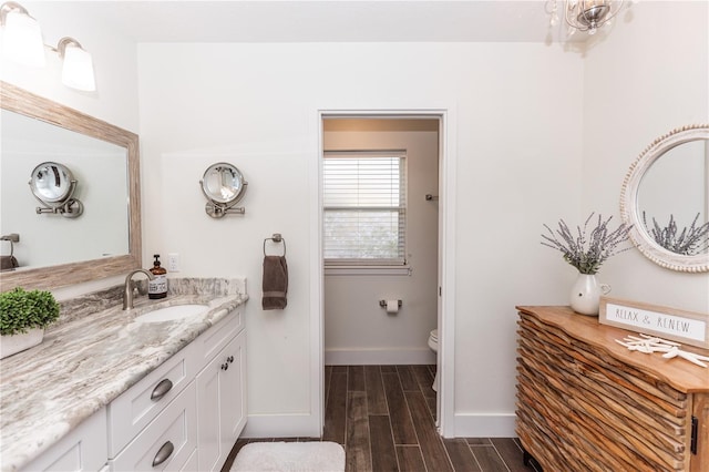 bathroom featuring baseboards, toilet, vanity, and wood finish floors