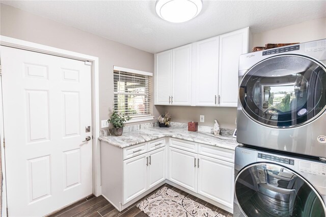 washroom featuring cabinet space, stacked washer and clothes dryer, a textured ceiling, and wood tiled floor