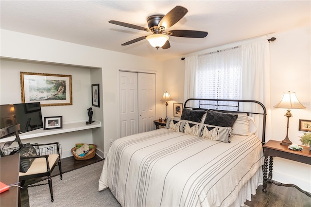 bedroom featuring a closet, baseboards, wood finished floors, and a ceiling fan